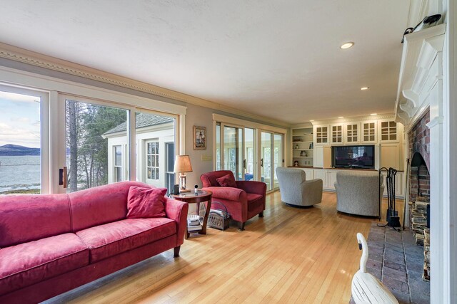 living area with light wood-style flooring, a water view, plenty of natural light, and french doors