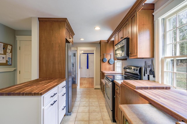 kitchen with recessed lighting, wooden counters, stainless steel appliances, and light tile patterned floors
