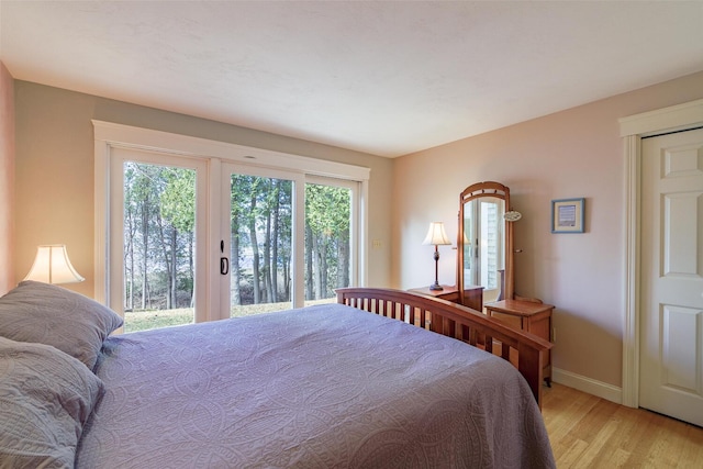 bedroom featuring light wood-type flooring, baseboards, and access to outside