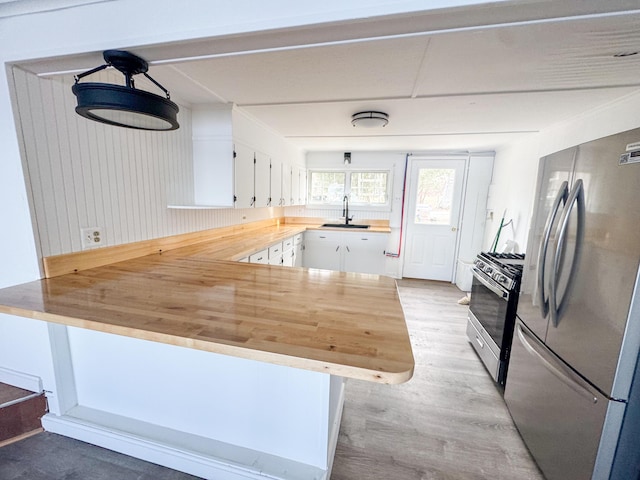 108/9 113 Sandy Beach Rd, Glenburn, ME 04401 - kitchen with white cabinets, a sink, wooden counters, stainless steel appliances, and a peninsula