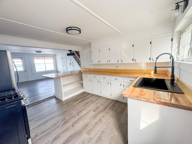108/9 113 Sandy Beach Rd, Glenburn, ME 04401 - kitchen with range with gas stovetop, light wood-style flooring, a sink, wooden counters, and a peninsula