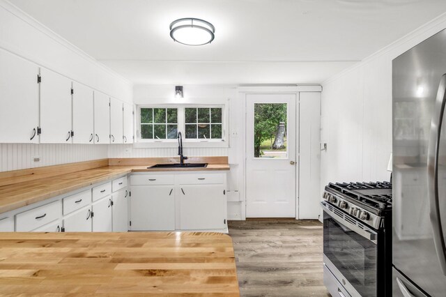108/9 113 Sandy Beach Rd, Glenburn, ME 04401 - kitchen featuring appliances with stainless steel finishes, wood finished floors, white cabinetry, wooden counters, and ornamental molding