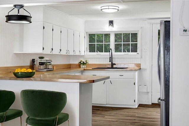 108/9 113 Sandy Beach Rd, Glenburn, ME 04401 - kitchen featuring wood finished floors, white cabinetry, freestanding refrigerator, a breakfast bar area, and light countertops