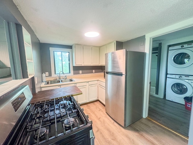 108/9 113 Sandy Beach Rd, Glenburn, ME 04401 - kitchen with freestanding refrigerator, range with gas cooktop, stacked washer / dryer, light wood finished floors, and a textured ceiling