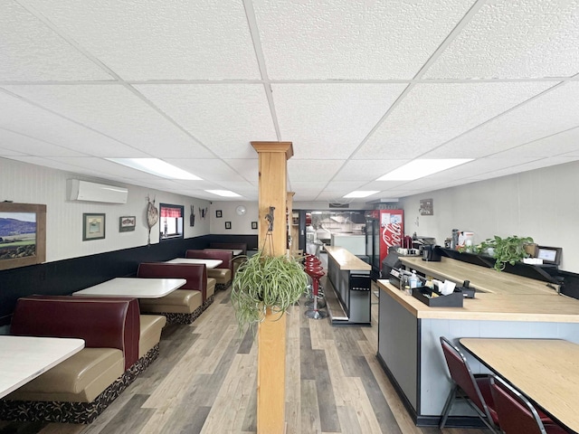 1716 Main St, Mapleton, ME 04757 - interior space with a wall mounted AC, a peninsula, open floor plan, a drop ceiling, and wood finished floors