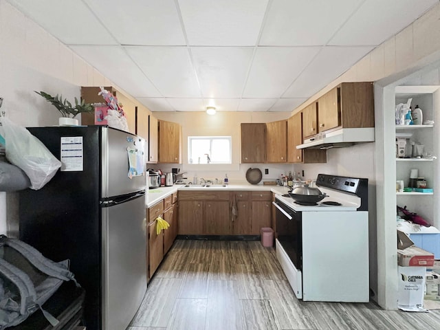 1716 Main St, Mapleton, ME 04757 - kitchen with freestanding refrigerator, electric range, a drop ceiling, under cabinet range hood, and brown cabinets