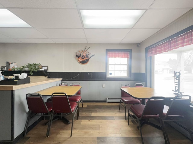 1716 Main St, Mapleton, ME 04757 - dining space featuring a paneled ceiling, a baseboard heating unit, wainscoting, and hardwood / wood-style flooring