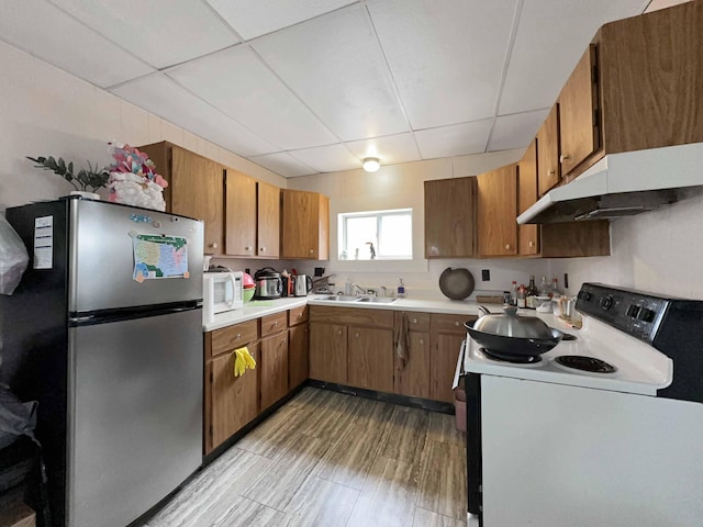 1716 Main St, Mapleton, ME 04757 - kitchen featuring a paneled ceiling, white appliances, under cabinet range hood, brown cabinets, and a sink