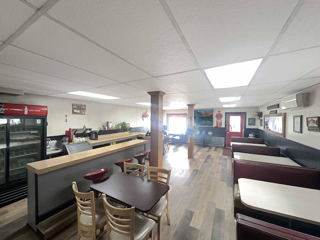 1716 Main St, Mapleton, ME 04757 - interior space featuring a wall mounted AC, ornate columns, wood finished floors, a drop ceiling, and beverage cooler