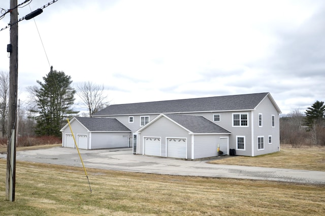 view of front of property featuring roof with shingles, a garage, driveway, and a front lawn