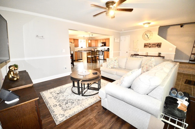 living room featuring dark wood-type flooring, baseboards, ornamental molding, and ceiling fan