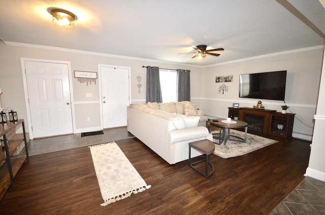 living area with baseboard heating, baseboards, crown molding, ceiling fan, and dark tile patterned flooring