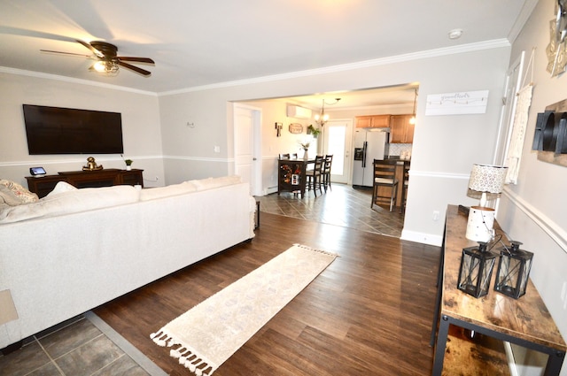 living area with dark wood-style flooring, ornamental molding, a baseboard heating unit, and ceiling fan with notable chandelier