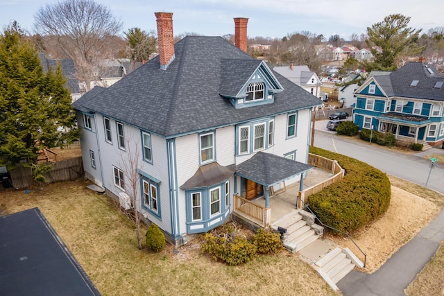 exterior space with a residential view, a chimney, a porch, fence, and a shingled roof