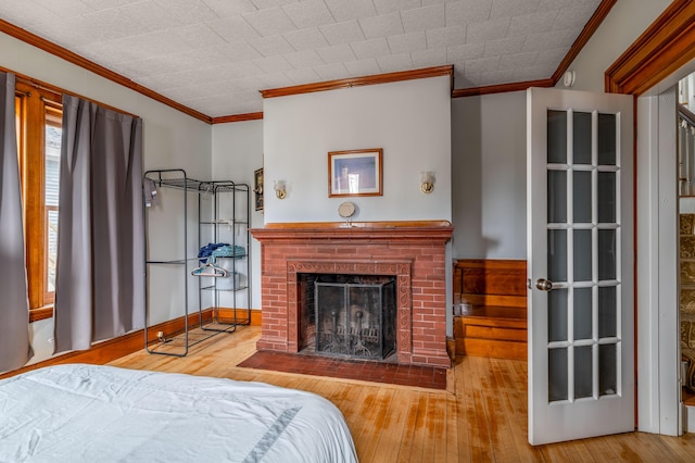 bedroom featuring crown molding, a brick fireplace, and hardwood / wood-style flooring