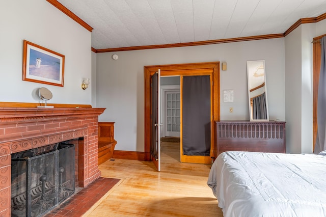 bedroom featuring baseboards, crown molding, wood-type flooring, and a brick fireplace