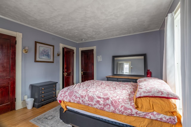 bedroom with ornamental molding, wood finished floors, and a textured ceiling