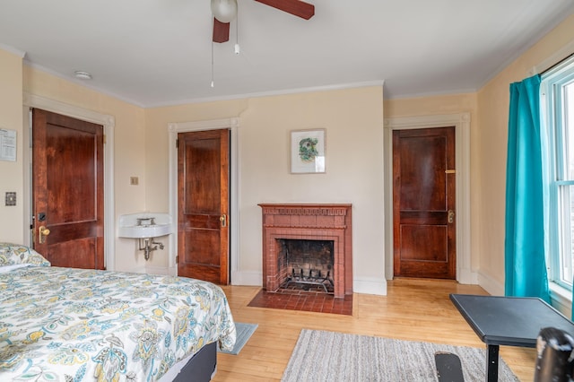 bedroom with ornamental molding, multiple windows, wood finished floors, and a fireplace