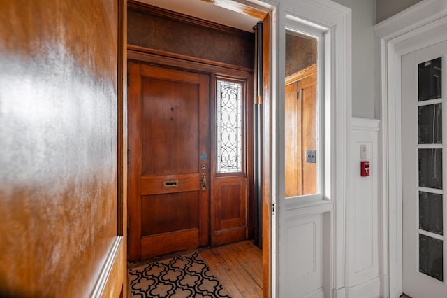 entrance foyer with a decorative wall, light wood-style floors, and a wainscoted wall