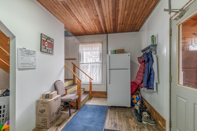 doorway with wooden ceiling, wood finished floors, wooden walls, and stairs