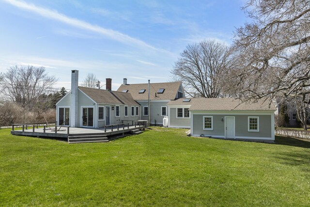 back of house featuring a lawn, a wooden deck, and a chimney