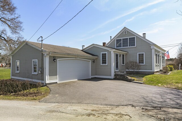 view of front facade featuring a garage, a chimney, and aphalt driveway
