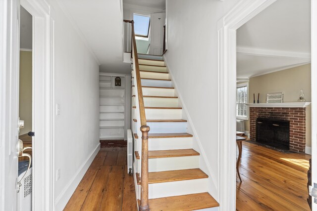 stairs with wood-type flooring, baseboards, radiator heating unit, and a fireplace