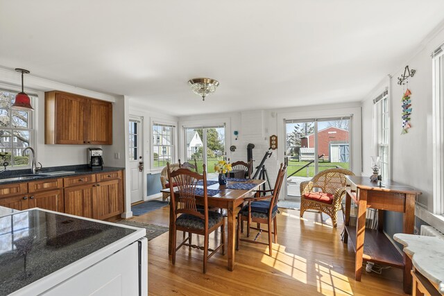 kitchen featuring brown cabinets, dark countertops, a sink, light wood-style floors, and pendant lighting