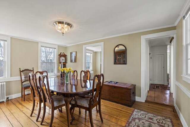 dining space with baseboards, ornamental molding, and light wood-style flooring