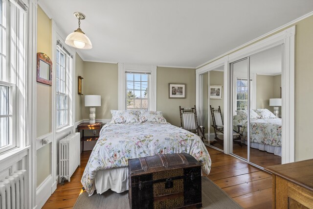 bedroom with wood-type flooring, crown molding, and radiator heating unit