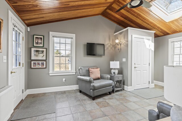 sitting room featuring a ceiling fan, radiator heating unit, vaulted ceiling with skylight, and wooden ceiling