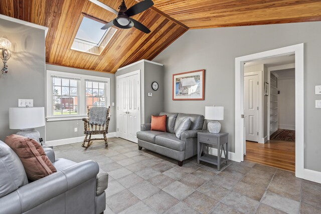 living room with ceiling fan, wooden ceiling, baseboards, and vaulted ceiling with skylight
