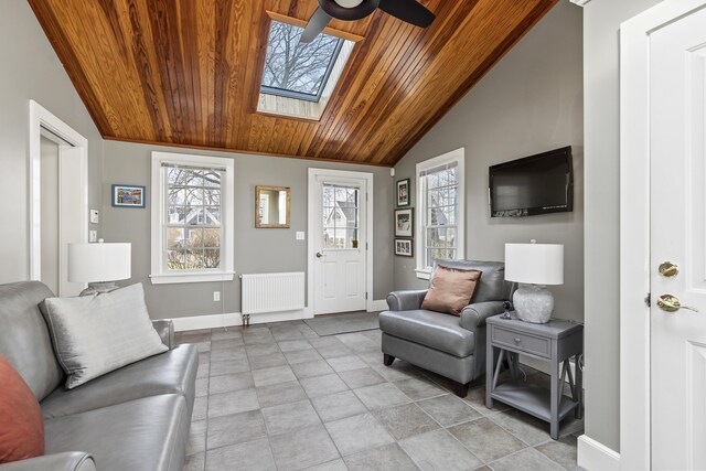 living area featuring radiator heating unit, wooden ceiling, baseboards, and lofted ceiling with skylight