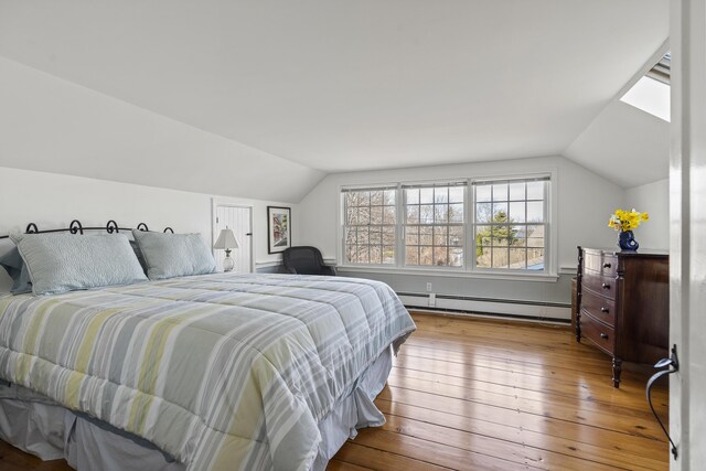 bedroom featuring baseboard heating, vaulted ceiling, and wood-type flooring