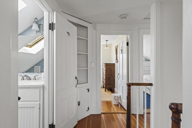 corridor with a skylight and wood finished floors