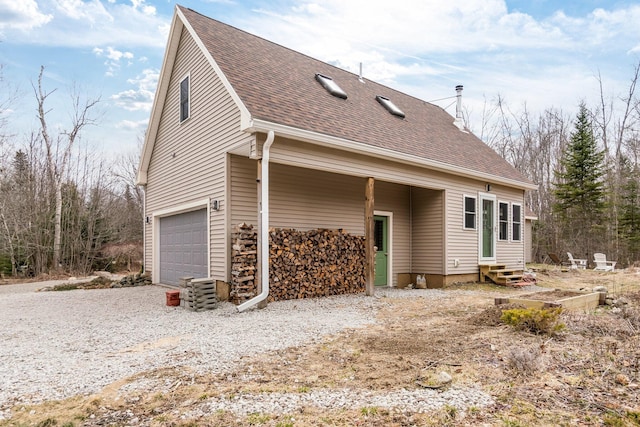 exterior space with entry steps, roof with shingles, and driveway