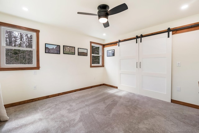 unfurnished bedroom with baseboards, carpet floors, and a barn door