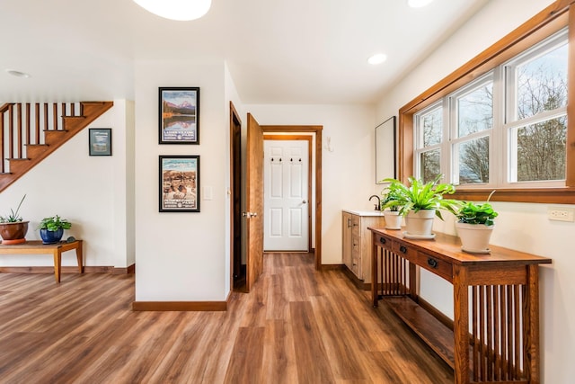 corridor with stairway, baseboards, wood finished floors, and recessed lighting