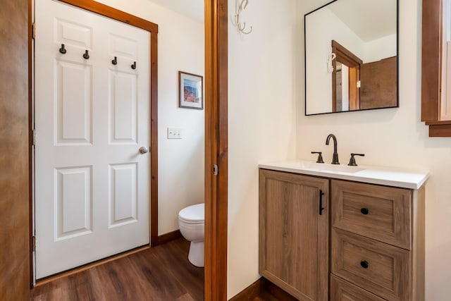 bathroom with wood finished floors, toilet, and vanity