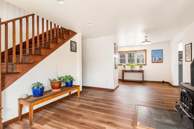 living area featuring stairway, wood finished floors, a wood stove, baseboards, and recessed lighting