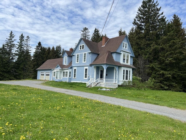 475 Main St, Van Buren, ME 04785 - victorian-style house with covered porch, a chimney, asphalt driveway, a front yard, and an attached garage