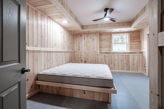 carpeted bedroom featuring ceiling fan, wood walls, and baseboards