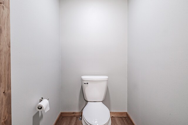 bathroom with toilet, wood finished floors, and baseboards