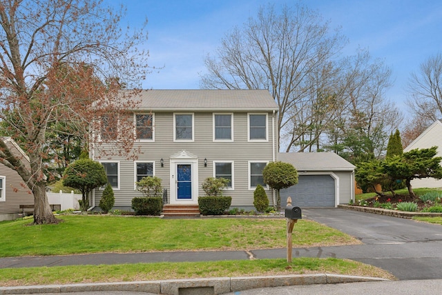 colonial-style house with driveway, an attached garage, and a front yard