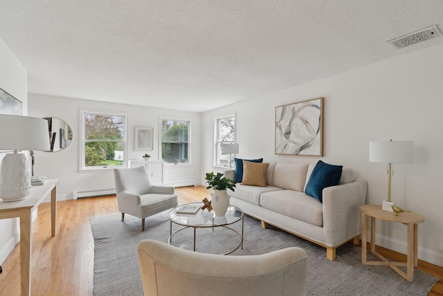 living room featuring a baseboard radiator, light wood-type flooring, baseboards, and a textured ceiling