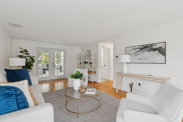 living room featuring wood finished floors, french doors, and a textured ceiling