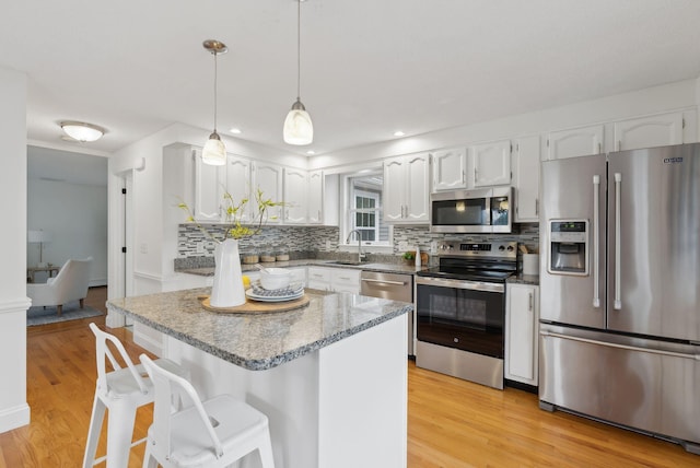 kitchen featuring appliances with stainless steel finishes, light wood-type flooring, backsplash, white cabinetry, and recessed lighting
