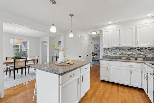 kitchen featuring light wood finished floors, backsplash, white cabinetry, stone countertops, and recessed lighting