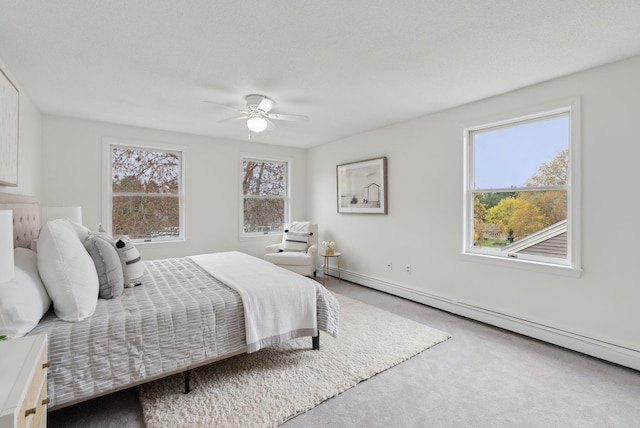 carpeted bedroom with a baseboard heating unit and ceiling fan