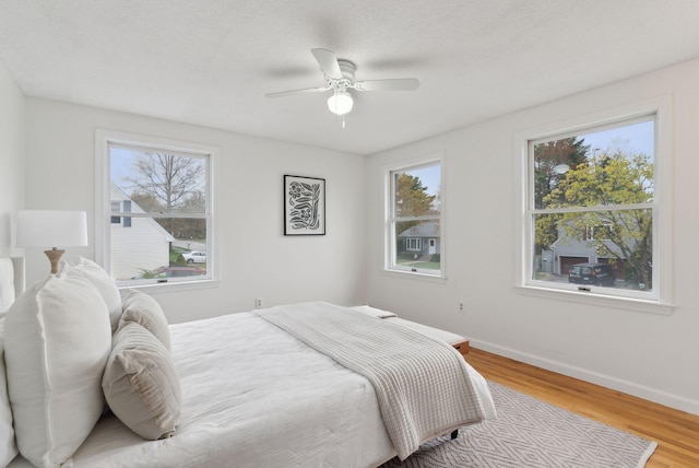 bedroom with wood finished floors, baseboards, and ceiling fan